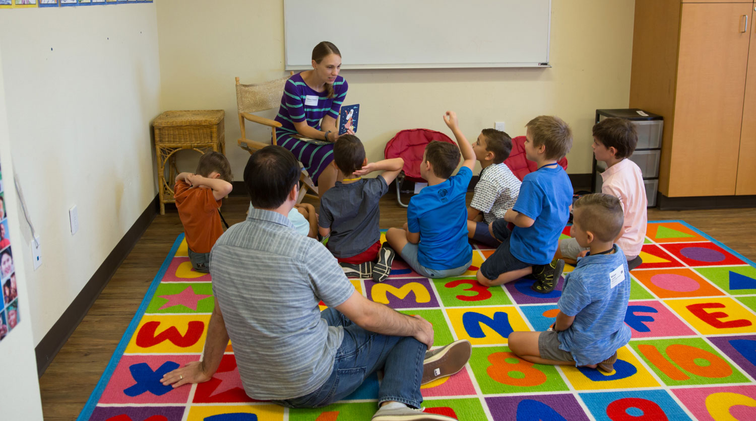 An adult talking to a group of children in a classroom